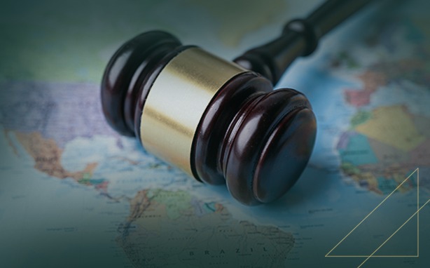 Wooden gavel with a golden band on a world map, North and South America visible.