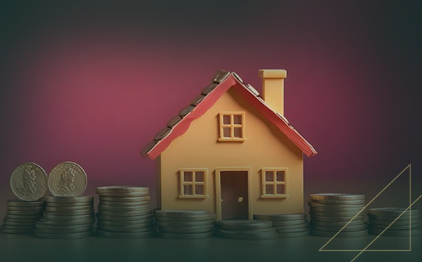 Toy house on stacks of coins against a magenta background.