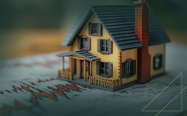Miniature house model on financial documents with graphs and text.