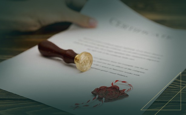 A document with a wax seal stamp and a red wax seal with striped string. A hand holds the top of the document.